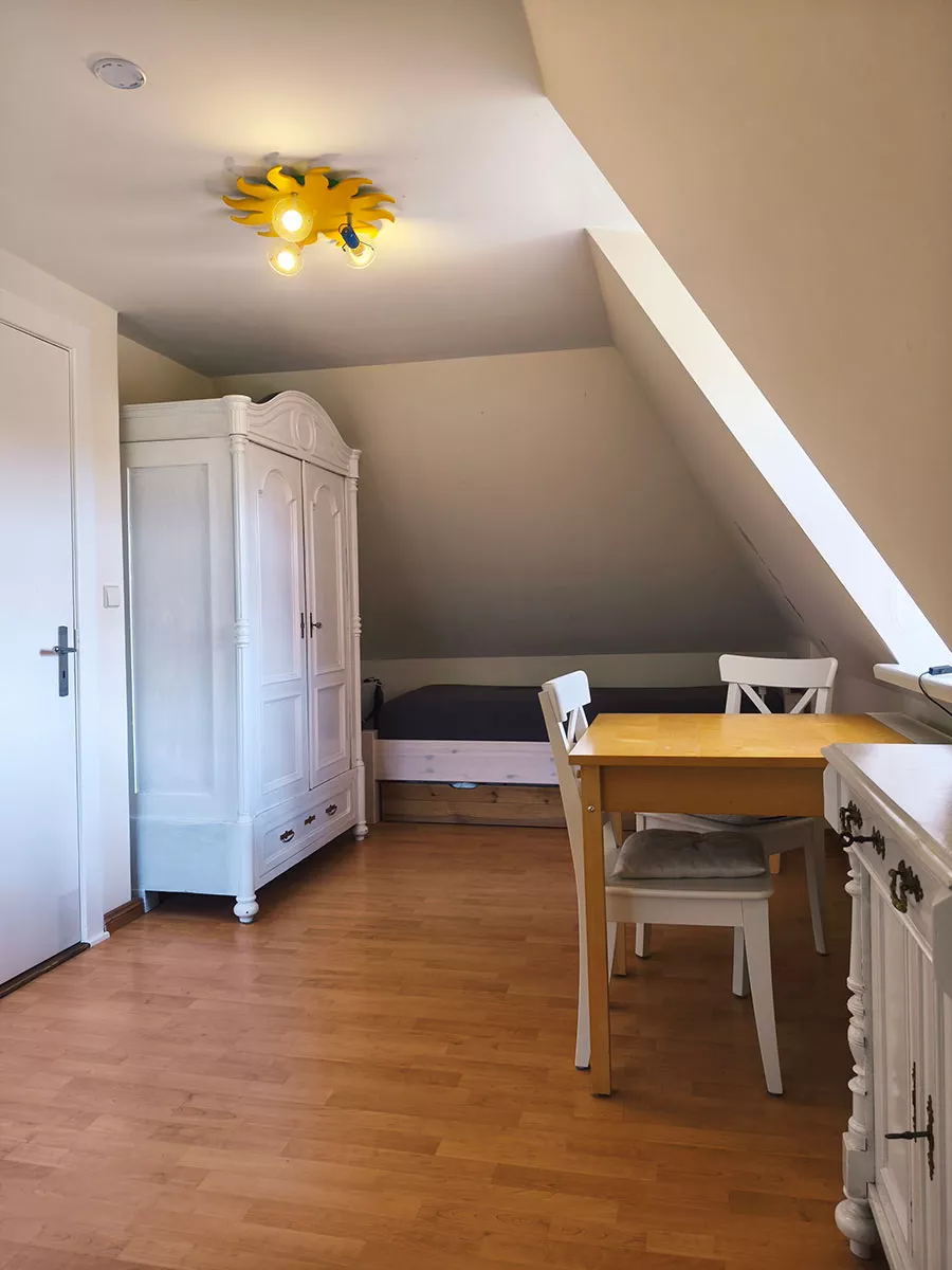 Ferienhaus Deichsonne – Schlafzimmer oben mit zwei Einzelbetten, Schrank und Sitzgelegenheit